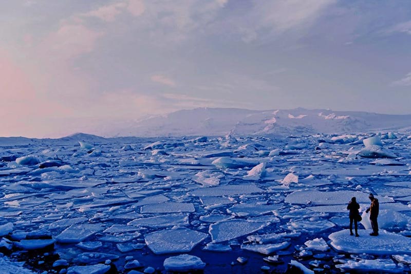 Two people in an ice block witness how ice melts down in small pieces, as a consequence of the increase of temperatures.