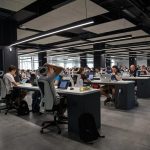 Decenas de personas trabajan en una oficina con ordenadores.
