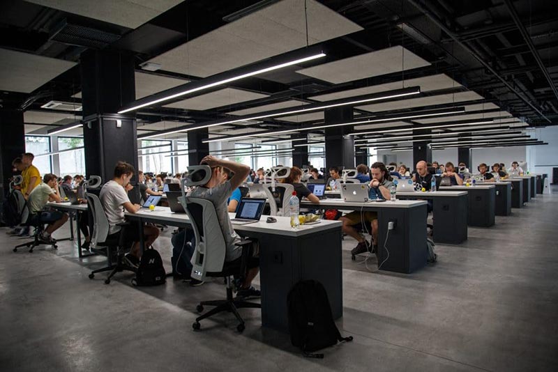 Dozens of workers in an office full of computers.
